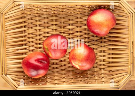 Several organic nectarines on a straw tray, macro, top view. Stock Photo