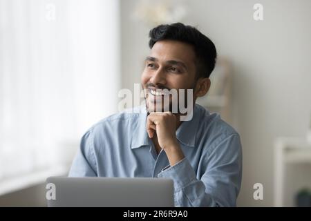 Happy young Indian business professional man thinking at home Stock Photo