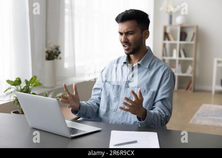 Annoyed worried young Indian business man having problems with laptop Stock Photo