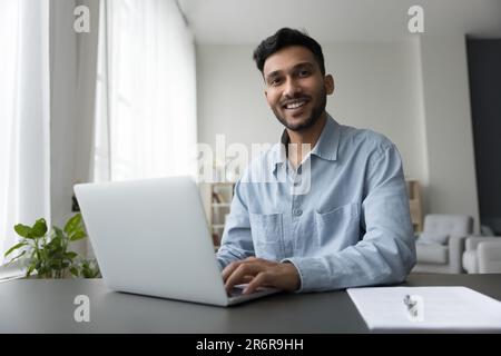 Happy young Indian freelance employee guy working at home Stock Photo