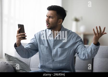 Mad frustrated young Indian guy having problems with online communication Stock Photo