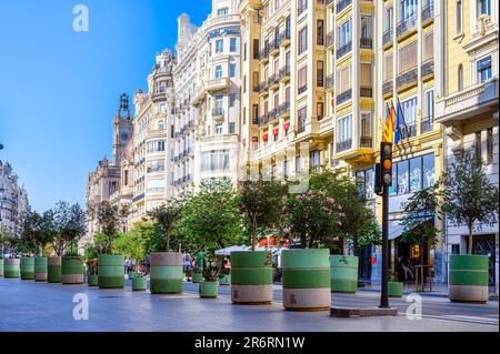 Valencia, Spain - July 15, 2022: Urban architecture with multiple buildings lining a street. Potted trees adorn the sidewalks. Stock Photo