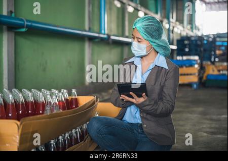 Processing Female Employee A woman employee in a beverage factory scrutinizes bottles on a ...