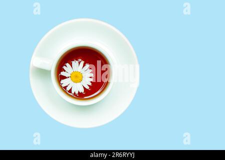 Chamomile tea in a white mug on a yellow background. Means for relaxation, calming tea. Stock Photo