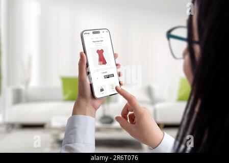 Concept of buying clothes online with a mobile phone. A woman uses an ecommerce website to shop concept Stock Photo