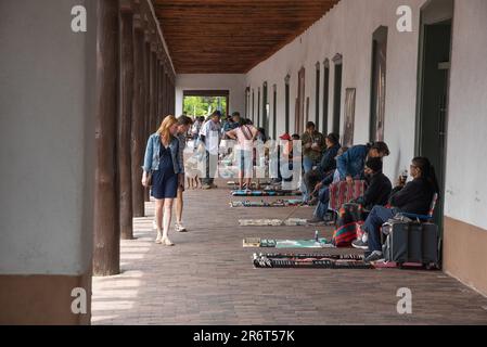Shoppers walk down the line of Native American vendors at the historic Palace of the Governors in the Santa Fe Plaza, Santa Fe, New Mexico, USA. Stock Photo