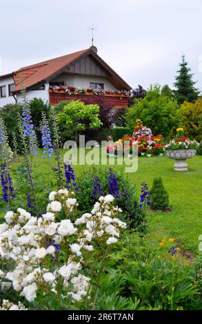 Pyramid of flowers in the garden, flowerpot with flowers, lawn, white roses in the garden Stock Photo