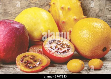 Tamarillo, kumquat, quince, kiwano, orange and apple on a wooden background Stock Photo