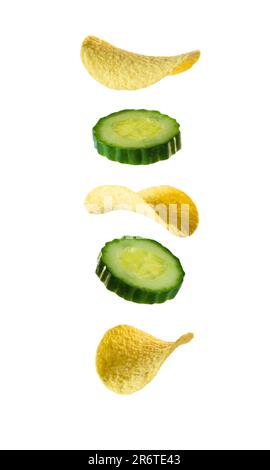 Potato chips and cucumber slices levitate on a white background. Falling potato chips and cucumber slices isolated on white background.  Flying potato Stock Photo