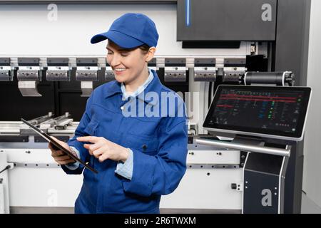Worker with digital tablet controls automatic machine tool in smart factory Stock Photo