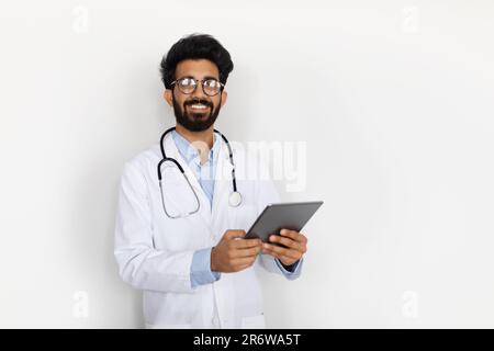 Handsome middle eastern doctor holding digital tablet, white background Stock Photo