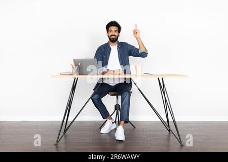 Inspired arab guy entrepreneur sitting at workplace, gesturing Stock Photo