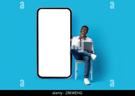 excited young black man independent contractor looking at smartphone, mockup Stock Photo
