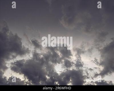 A scenic wide view of heavy gray stormy clouds gathering in the sky creating a moody atmospheric natural background Stock Photo