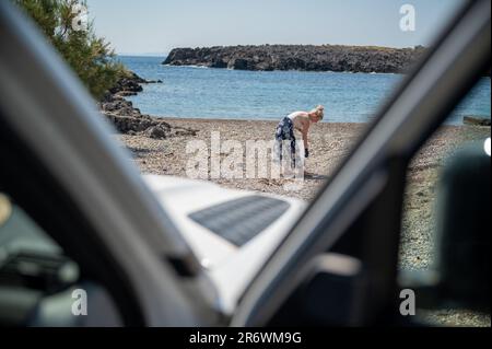 Blonde woman in dress collects plastic waste on a beach Stock Photo