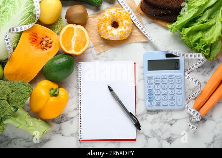 Food products, notebook with calculator on white marble table, flat lay. Weight loss and calorie counting concept Stock Photo