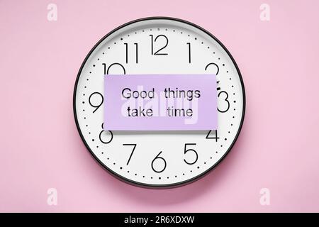 Card with phrase Good Things Take Time and clock on pink background, top view. Motivational quote Stock Photo