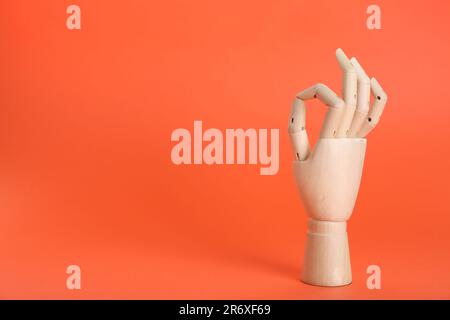 Wooden mannequin hand showing okay gesture on orange background. Space for text Stock Photo