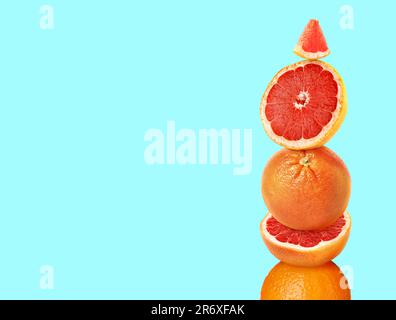 Stacked cut and whole grapefruits on light blue background, space for text Stock Photo