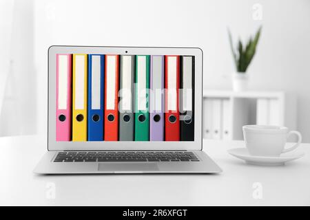 Store and organize information. Modern laptop with hardcover office folders on screen Stock Photo