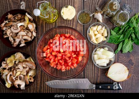 Chopped Plum Tomatoes in a Glass Mixing Bowl: Diced tomatoes with wild mushrooms, basil, garlic, and other ingredients Stock Photo