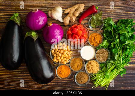 Vegan Roasted Eggplant and Chickpea Curry Ingredients: Raw aubergines, red onions, spices, and other Indian curry ingredients Stock Photo