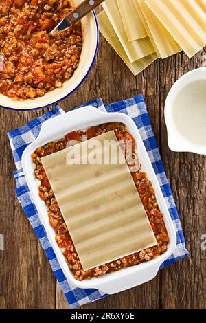 Preparing Lasagna in Rectangular Casserole Dish. Lasagna pasta sheet on top of ragu or bolognese sauce and bechamel or white sauce Stock Photo