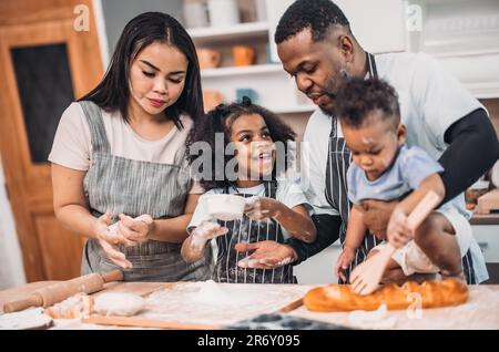 Family members cook homemade pizza dough in funny and playful ways. Mixing ingredients like salt, sugar, milk, yeast, oil then rubbing, massaging, pre Stock Photo