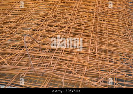 Iron metal braided rusty yellow reinforcing welded industrial construction mesh from reinforcement and corrugated wire. Texture, background. Stock Photo