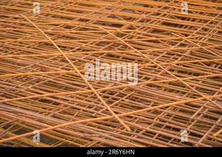 Iron metal braided rusty yellow reinforcing welded industrial construction mesh from reinforcement and corrugated wire. Texture, background. Stock Photo