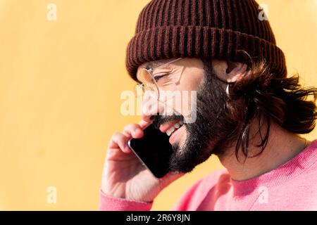 man talking on mobile phone in a yellow background Stock Photo