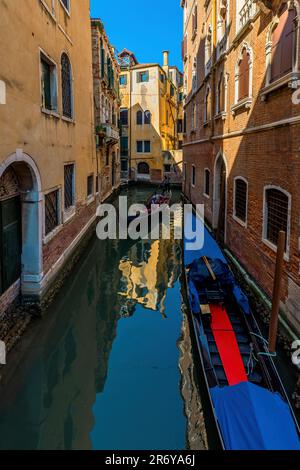 Gondolas on narrow canal among old colorful typical buildings in Venice, Italy. Stock Photo