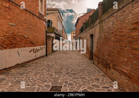 Narrow street of Murano with brickwall houses in Venice, Italy. Stock Photo