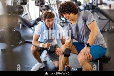 Fitness, sport, exercising concept. Fit man exercising together with his personal trainer in gym. Stock Photo
