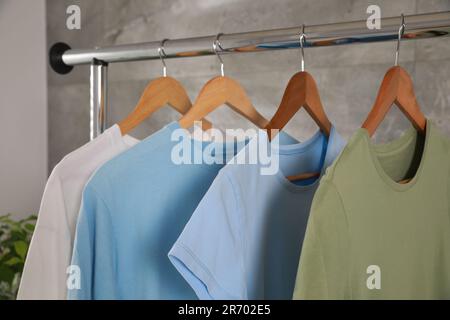 Different clean T-shirts hanging on rack indoors Stock Photo