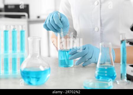 Scientist taking sample of light blue liquid in laboratory, closeup Stock Photo