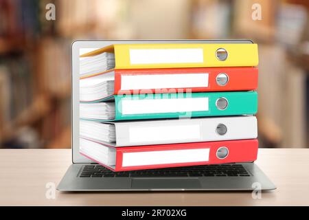 Store and organize information. Hardcover office folders getting out of modern laptop in archive room Stock Photo