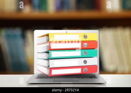 Store and organize information. Hardcover office folders getting out of modern laptop in archive room Stock Photo