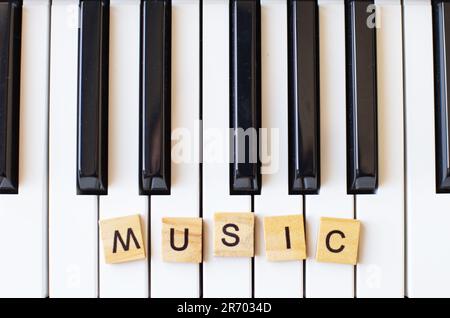 Word music made by wooden cubes on a s ynthesizer keys black and white background with copy space for your text. Piano octave close up top view. Keybo Stock Photo