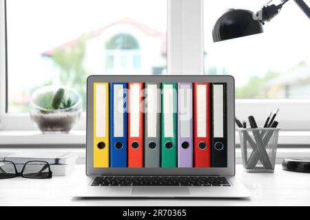 Store and organize information. Modern laptop with hardcover office folders on screen in office Stock Photo