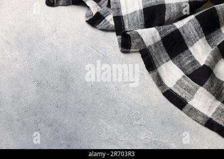 Black checkered tablecloth on light gray textured table, space for text Stock Photo