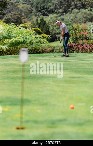 Distant view of woman playing golf, Bedugul, Bali, Indonesia Stock Photo