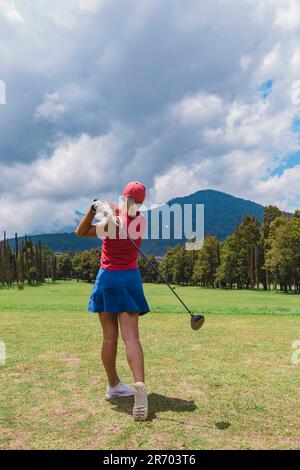 Woman swinging club while playing golf at golf course, Bedugul, Bali, Indonesia Stock Photo