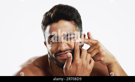 Pimple pop, Indian man and struggling model doing skincare and wellness routine for acne. Isolated, white background and beauty treatment for Stock Photo