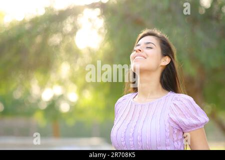 Happy woman breathing fresh air wearing earbud in a green park Stock ...