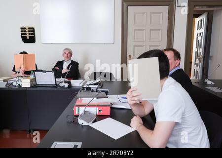 12 June 2023, Hamburg: The two defendants cover their faces next to lawyer Andreas Trode (2nd from left) and lawyer Thomas Domanski (r, half covered) as the state protection trial continues in the Criminal Justice Building. The federal prosecution accuses an 18-year-old Russian from Bremerhaven and a 16-year-old German-Kosovar from Iserlohn of supporting the 'Islamic State' (IS) from Germany or, in the case of the older defendant, joining the IS as members. According to the indictment, the younger defendant planned to carry out an attack in Germany in the name of the IS. Photo: Ulrich Perrey/d Stock Photo