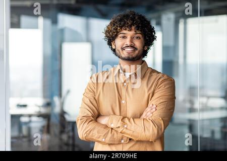 Portrait young successful Indian businessman, man in shirt smiling and looking at camera, programmer working inside modern office building young investor financier satisfied with achievement results Stock Photo