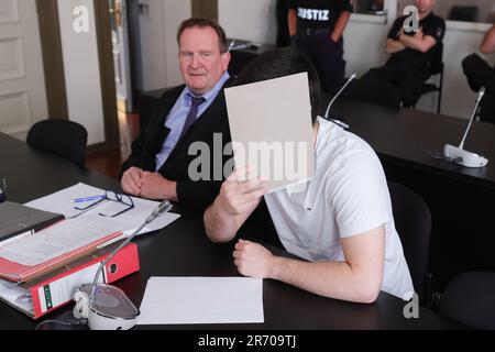 Hamburg, Germany. 12th June, 2023. One of the two defendants covers his face next to lawyer Thomas Domanski (l) as the state protection proceedings continue in the Criminal Justice Building. The federal prosecution accuses an 18-year-old Russian from Bremerhaven and a 16-year-old German-Kosovar from Iserlohn of supporting the 'Islamic State' (IS) from Germany or, in the case of the older defendant, joining the IS as members. According to the indictment, the younger defendant planned to carry out an attack in Germany in the name of the IS. Credit: Ulrich Perrey/dpa/Alamy Live News Stock Photo