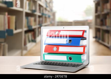 Store and organize information. Hardcover office folders getting out of modern laptop in archive room Stock Photo