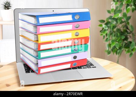 Store and organize information. Hardcover office folders getting out of modern laptop Stock Photo